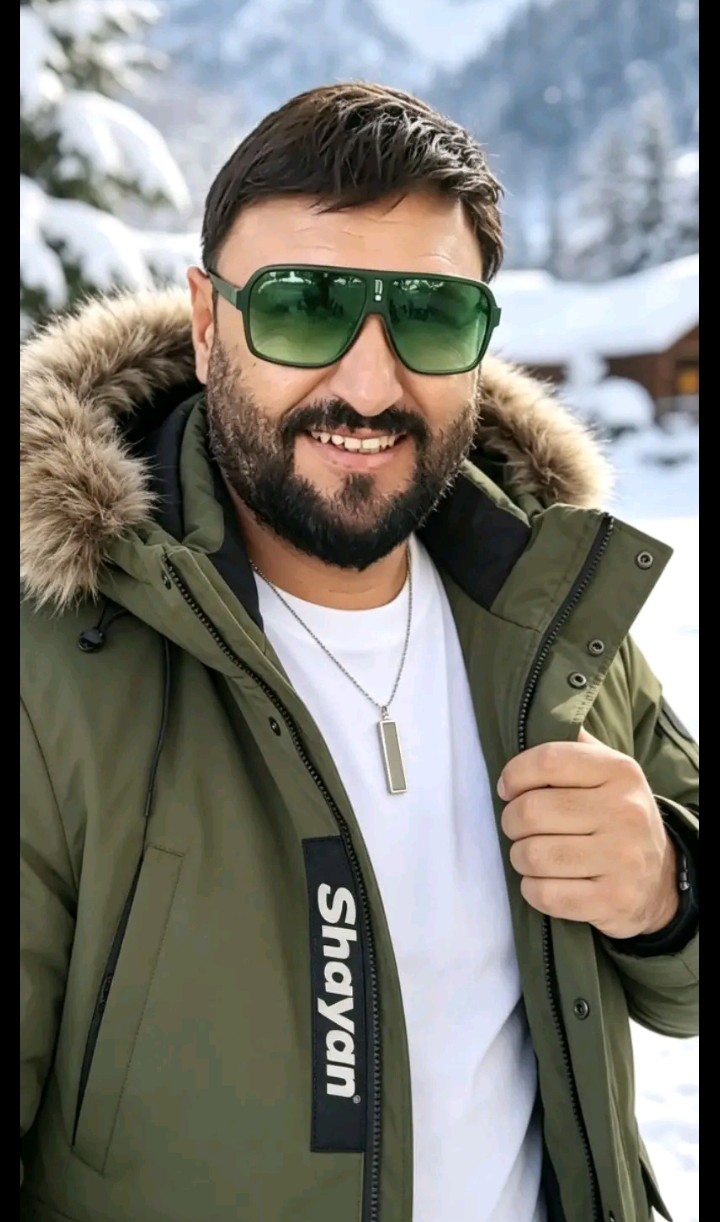 Cristiano Max de óculos verdes e jaqueta verde com capuz de pelo na neve